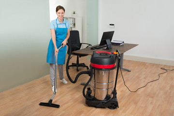 Worker Cleaning Floor With Vacuum Cleaner