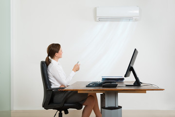 Businesswoman Using Air Conditioner In Office