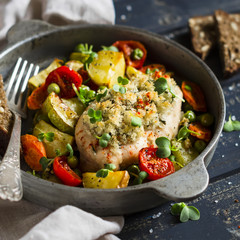baked chicken breast with vegetables in a vintage pan on a dark wooden background