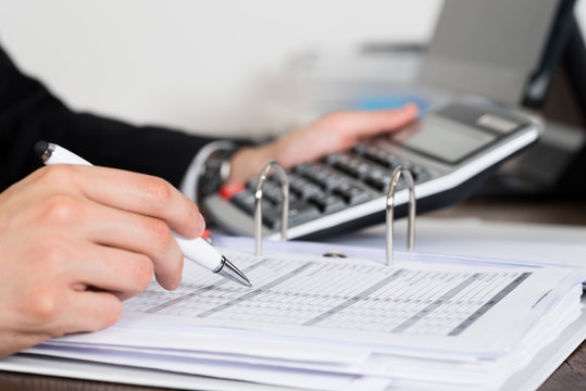 Businessperson Calculating Invoice In Office