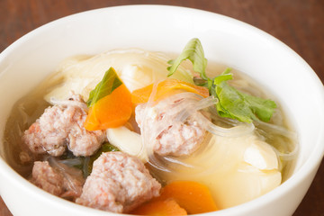 clear soup with pork in white plate put on wooden background, Thai cuisine.