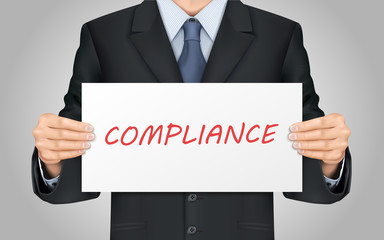 businessman holding compliance word poster