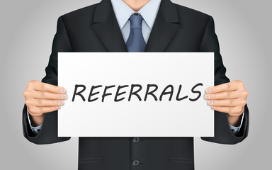 businessman holding referrals word poster