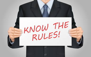 businessman holding know the rules poster