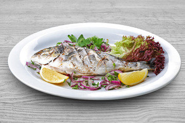 grilled fish with vegetables on white plate