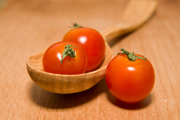 Red tomatoes in a wooden spoon on a wooden surface