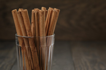true cinnamon sticks in glass on wooden table, selective