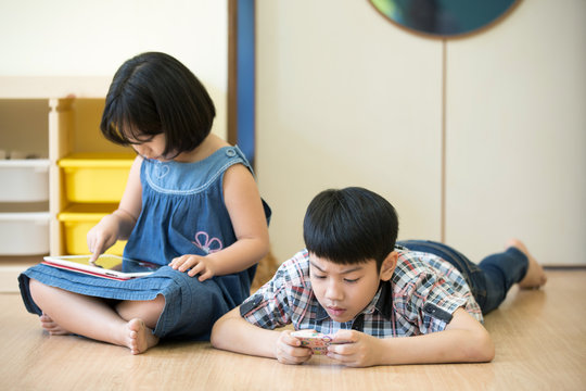 Little Asian boy and girl are playing together with a computer t
