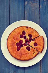 pie with raspberries on plate on blue wooden background