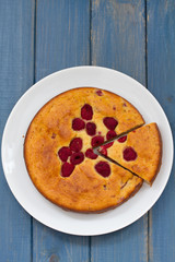 pie with raspberries on plate on blue background