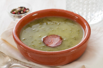 portuguese soup caldo verde in ceramic dish and spoon with glass of water