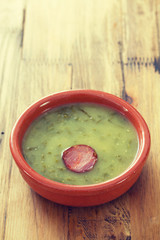 portuguese soup caldo verde in ceramic dish on brown background