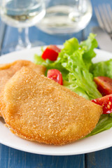 portuguese meat cookies with fresh salad on white dish on blue wooden background