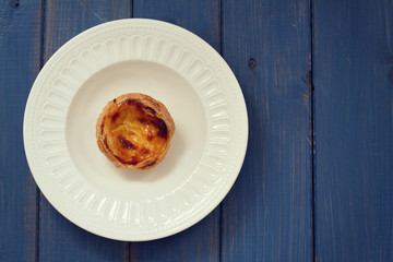 portuguese egg cookie on white dish on blue wooden background
