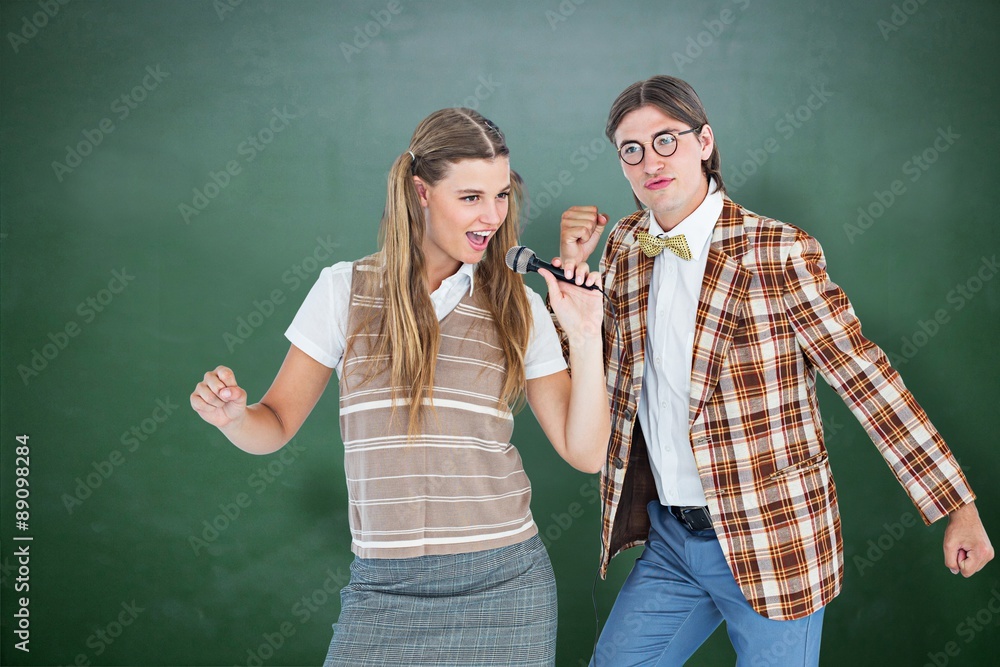 Poster composite image of happy geeky hipsters singing with microphone