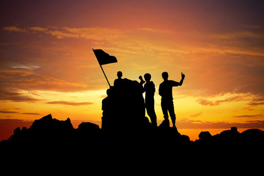 Silhouette of a champion on mountain peak at sunset.
