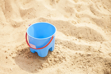 Fototapeta na wymiar Blue empty bucket with red handle on sand