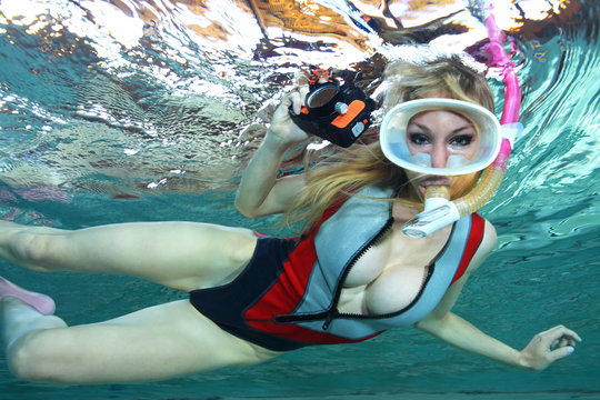 Sexy female snorkeler with neoprene swimsuit and underwater camera 