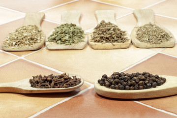 Cloves and black pepper, with several kinds of aromatic dried herbs behind