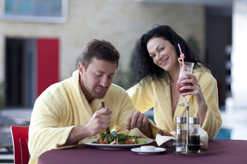 Cute couple in bathrobes having breakfast together at hotel