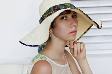 Beautiful young girl with beauty skin and a thoughtful look in the big white hat