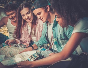 Multiracial friends tourists in a park with map