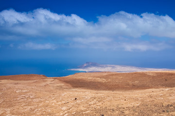 View of the La Graciosa island from a slant of Mount Mirador del Rio on background deep blue sky and Atlantic Ocean. Lanzarote, Canary Islands, Spain