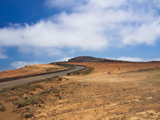 The road to the top of the mountain Mirador del Rio on background blue sky. Gravel slopes of the volcano on the island of Lanzarote. Canary Islands, Spain