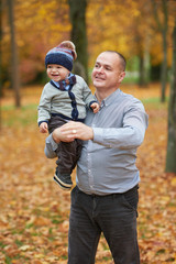 father with son walking in autumn forest