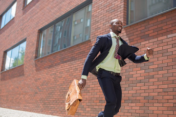 african black young businessman running in a city street