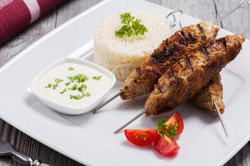 Barbecued kofta - kebeb with rice and vegetables on a plate.