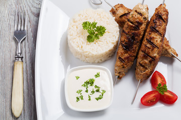 Barbecued kofta - kebeb with rice and vegetables on a plate.