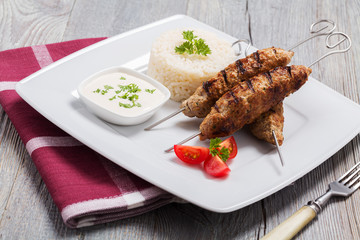 Barbecued kofta - kebeb with rice and vegetables on a plate.