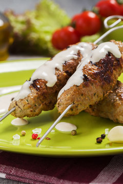 Barbecued kofta - kebeb topped with sauce with vegetables on a p