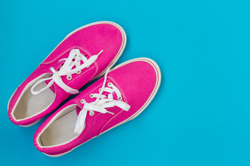 Pink sneakers with laces on a blue