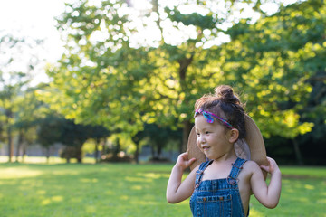 Fototapeta premium 大きすぎる麦藁帽子で遊ぶ女の子