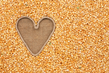 The symbolic heart made of rope lies on sackcloth and peas grain