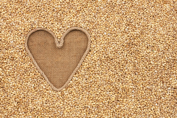 The symbolic heart made of rope lies on sackcloth and pearl barl