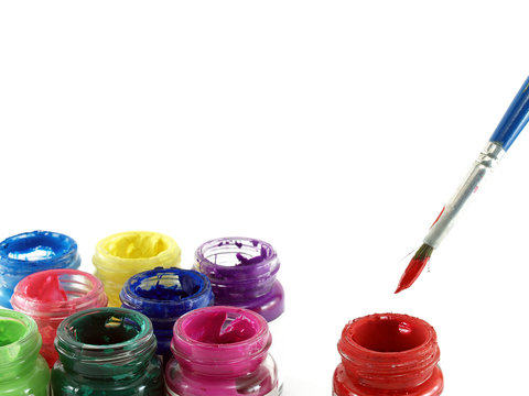 paintbrush dipped red colour and group of colorful bottles of poster color