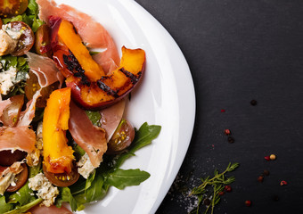 Delicious salad with grilled peaches and prosciutto