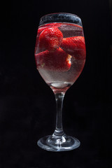 Strawberries in wine glass with water.