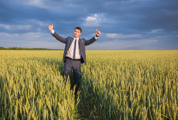 happy farmer, businessman, standing in wheat field with his