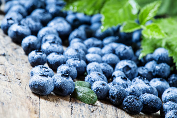 Fresh blueberries and green leaves on the old wooden background,