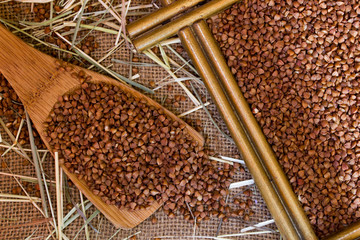 Wooden spoon with buckwheat on burlap background texture