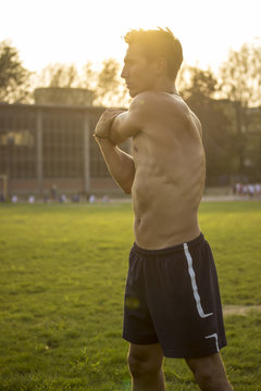 Muscular athlete stretching upper body. Intentionall lens flare.