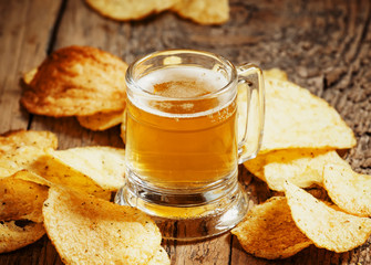 Light beer and chips on the old wooden background, selective foc