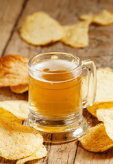 Light beer and chips on the old wooden background, selective foc