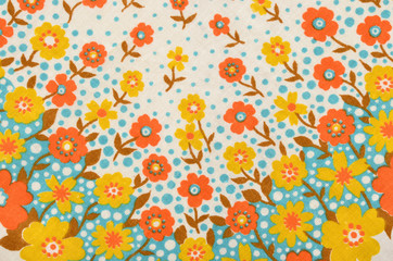 Floral pattern on fabric. Yellow and orange flowers with blue dots print as background.