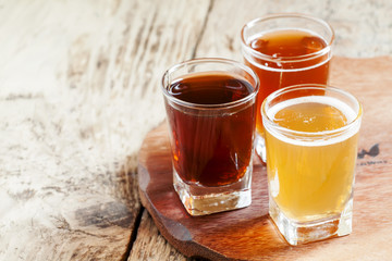 Three kinds of beer on old wooden background, selective focus