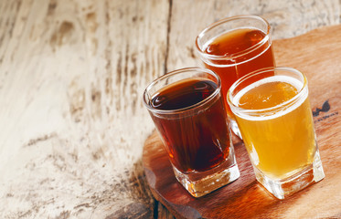 Three kinds of beer on old wooden background, selective focus